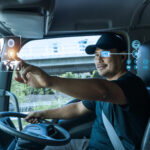 Male semi-truck driver behind the wheel in the cab.